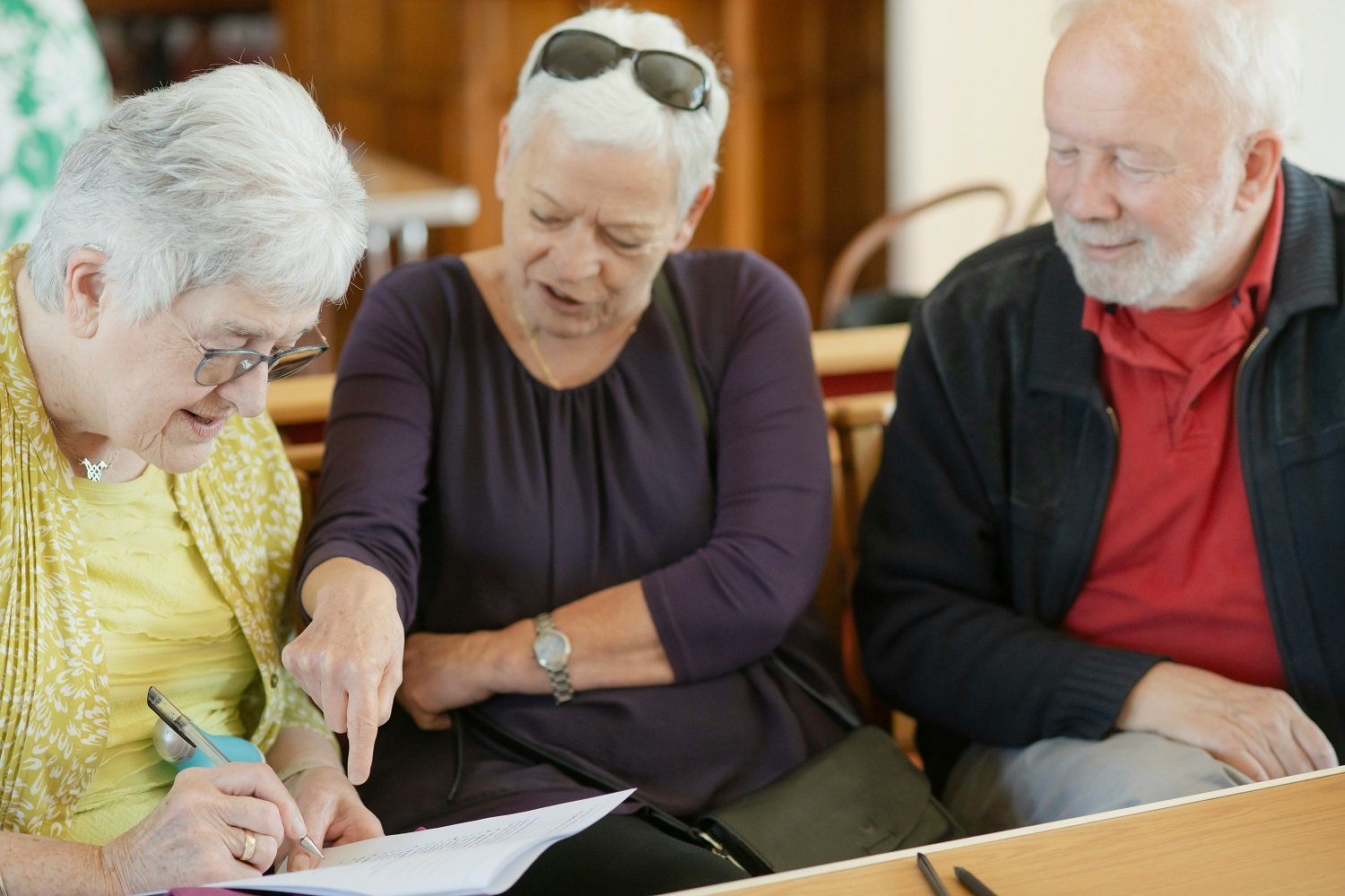 Three older people filling in a form together
