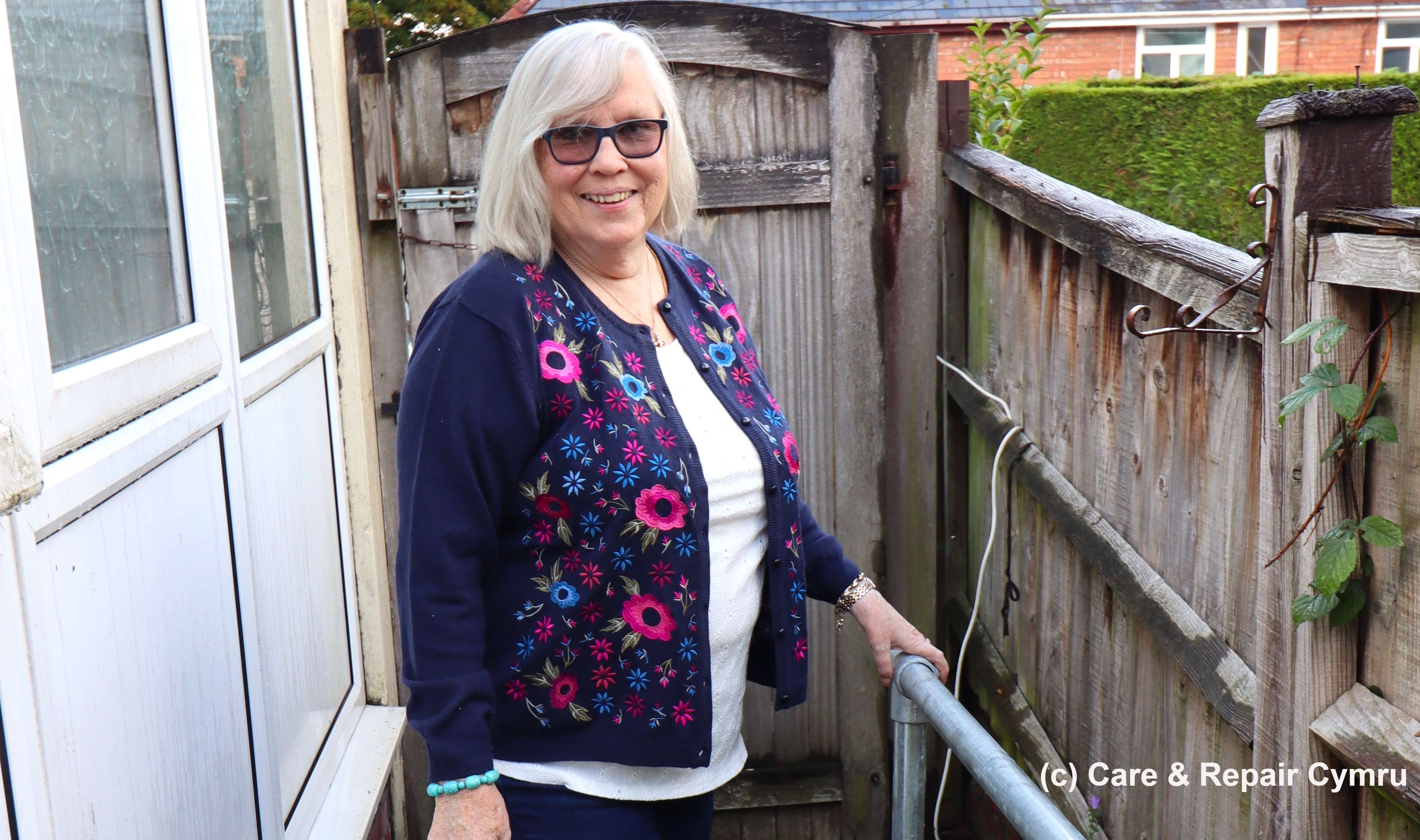 Woman stood on slope outside house